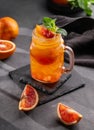 Freshly squeezed blood orange juice with ice, mint and a slice of fruit in a jar on a dark background with citrus fruits and Royalty Free Stock Photo