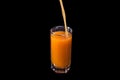 fruit juice is poured into a glass. Peach, orange or carrot on an isolated black background