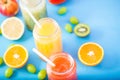 Freshly squeezed fruit juice, smoothies yellow orange green blue banana lemon apple orange kiwi grape strawberry on bright blue ba Royalty Free Stock Photo