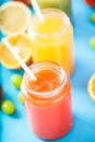 Freshly squeezed fruit juice, smoothies yellow orange green blue banana lemon apple orange kiwi grape strawberry on bright blue ba Royalty Free Stock Photo