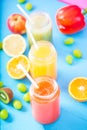 Freshly squeezed fruit juice, smoothies yellow orange green blue banana lemon apple orange kiwi grape strawberry on bright blue ba Royalty Free Stock Photo