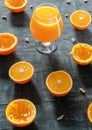 Freshly squeezed orange juice in a glass for brandy. Next to the glass are sliced oranges and zest. Dark background. view from Royalty Free Stock Photo