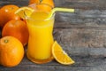 Freshly squeezed orange juice in glass with orange fruits on wooden background Royalty Free Stock Photo