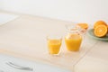 Freshly squeezed orange juice in glass and jug, fruits on plate on white furniture in modern minimalist kitchen Royalty Free Stock Photo