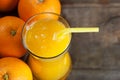 Freshly squeezed orange juice in glass with orange fruits on wooden background Royalty Free Stock Photo