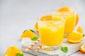 Freshly squeezed orange juice with ice in a glass with a straw on a wooden board on a light background with fresh oranges. Royalty Free Stock Photo