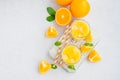 Freshly squeezed orange juice with ice in a glass with a straw on a wooden board on a light background with fresh oranges. Royalty Free Stock Photo