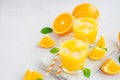 Freshly squeezed orange juice with ice in a glass with a straw on a wooden board on a light background with fresh oranges. Royalty Free Stock Photo