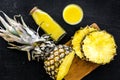 Freshly squeezed pineapple juice near fruit slices on black background top view Royalty Free Stock Photo