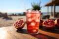 Freshly squeezed pomegranate in glass with ice on table at beach. Generative AI