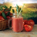 Freshly squeezed tomato juice in a glass cup, a basket with ripe tomatoes Royalty Free Stock Photo