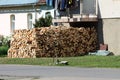 Freshly stacked firewood prepared for cold winter days in front of family house balcony surrounded with grass and paved road