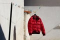 Freshly washed bright red winter jacket left to dry on coat hanger attached to clothesline filled with clothespins Royalty Free Stock Photo