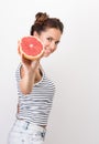 Freshness and vivacity. Young cheerful woman holding half a grapefruit at arm