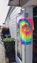 A bright tie dye Morro Bay t shirt on hanger outside entrance of store