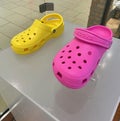 A photo of two Women's Croc shoes in bright pink and yellow