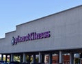 Planet Fitness Gym sign out front showing several front windows against a blue sunny sky background