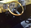 A steering wheel inside a gold custom designed 1950 Ford Model F1 with grey seat covers