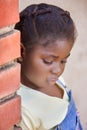 frican girl with braids hairstyle leaning on a brick wall