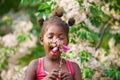 frican girl with ponytails joyfully smelling the flowers in the garden