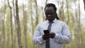 Frican man with shirt and tie using smartphone in he forest