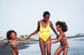 Frican sister twins running on the beach with smiling mother - Black family people having fun on summertime - Vacation, travel and Royalty Free Stock Photo