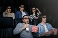 Friday night fun. Bewildered people in 3D glasses watching scary movie in cinema