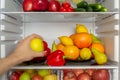 Fridge is filled with vegetables, fruits. Hand takes food from the refrigerator Royalty Free Stock Photo