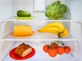 Fridge with some green, yellow and red food