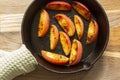 Fried apple, Pink Lady variety, in a cast iron frying pan. On a chopping board in a kitchen