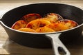 Fried apple, Pink Lady variety, in a cast iron frying pan. On a chopping board in a kitchen