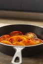 Fried apple, Pink Lady variety, in a cast iron frying pan. On a chopping board in a kitchen