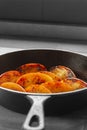 Fried apple, Pink Lady variety, in a cast iron frying pan. On a wooden chopping board