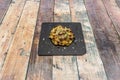 Fried artichoke flower with sautÃÂ©ed pieces of serrano ham, marinade scales and chopped chives on a square slate plate Royalty Free Stock Photo