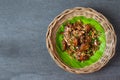 Fried bacon with garlic and pepper on banana leaf in basket on the concrete table Royalty Free Stock Photo