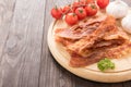 Fried bacon, tomato and garlic on the wooden board