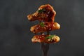 Fried barbecue chicken wings close up skewered on carving fork