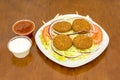 Fried battered round falafel portions on a bed of iceberg lettuce, strips of fresh purple onion and slices of raw tomato Royalty Free Stock Photo