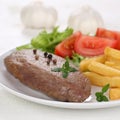 Fried beef steak meat meal with fries, vegetables and lettuce on Royalty Free Stock Photo