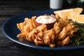 Fried blooming onion with dipping sauce served on dark wooden table, closeup Royalty Free Stock Photo