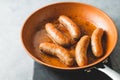 Fried bratwurst (pork sausages) on a frying pan close-up on the kitchen table, view from above, copy space Royalty Free Stock Photo