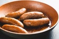 Fried bratwurst pork sausages on a frying pan close-up on the kitchen table, view from above, copy space Royalty Free Stock Photo