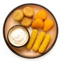 Fried breaded brie and camembert nuggets and mozzarella sticks on a rustic ceramic plate with white dip on white from above Royalty Free Stock Photo