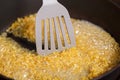 Fried bulgur in a frying pan. Caramel flavored wheat grains stirring with a kitchen spatula in boiling oil