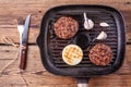 Fried burger beef cutlets with onion and garlic on grill pan with fork and knife