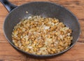 Fried button mushrooms with onion in frying pan on table Royalty Free Stock Photo