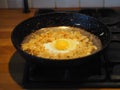 Home cooking. Fried cabbage, egg in a black pan over a fire. A bachelor breakfast is being prepared Royalty Free Stock Photo