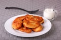 Fried cakes on white plate, fork and cup of milk