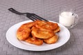 Fried cakes on white plate, plastic spatula and cup of milk