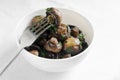 Fried champignons with garlic and parsley in a white bowl with a fork with a mushroom. The concept of vegetarian food. Royalty Free Stock Photo